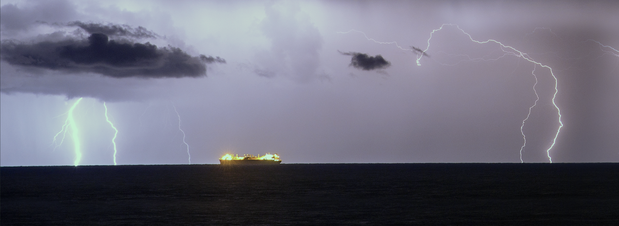A ship sails in the Mediterranean Sea as lightning strikes the sky as seen from the Israeli coast on November 24, 2014. 